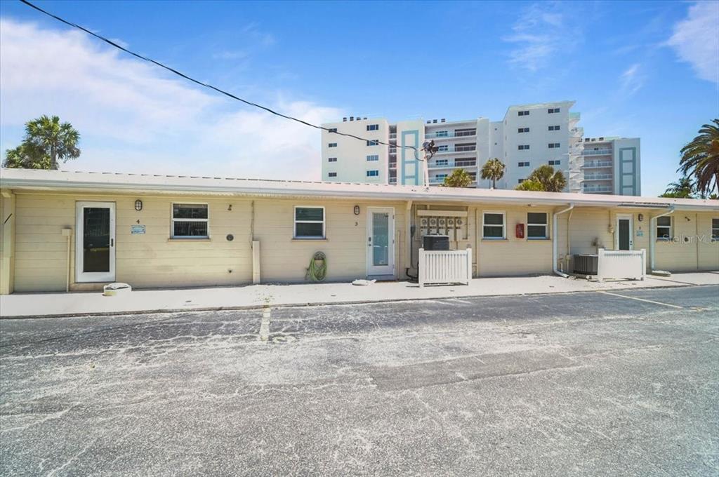 A single-story beige apartment building with multiple unit doors and windows faces a parking lot — 5830 MIDNIGHT PASS ROAD UNIT 3, SARASOTA, FL
