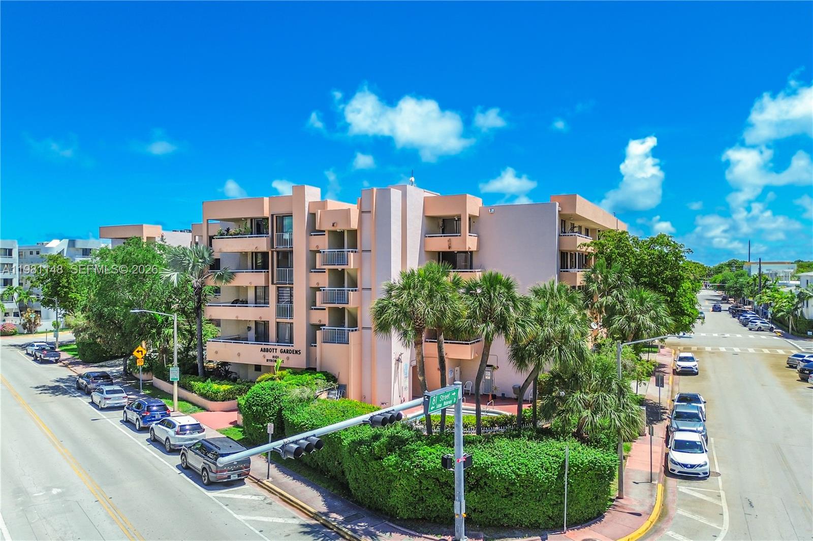 An exterior view of a multi-story peach-colored apartment building with balconies and palm trees — 8101 Byron Ave # 509, Miami Beach FL 33141, MIAMI BEACH, FL