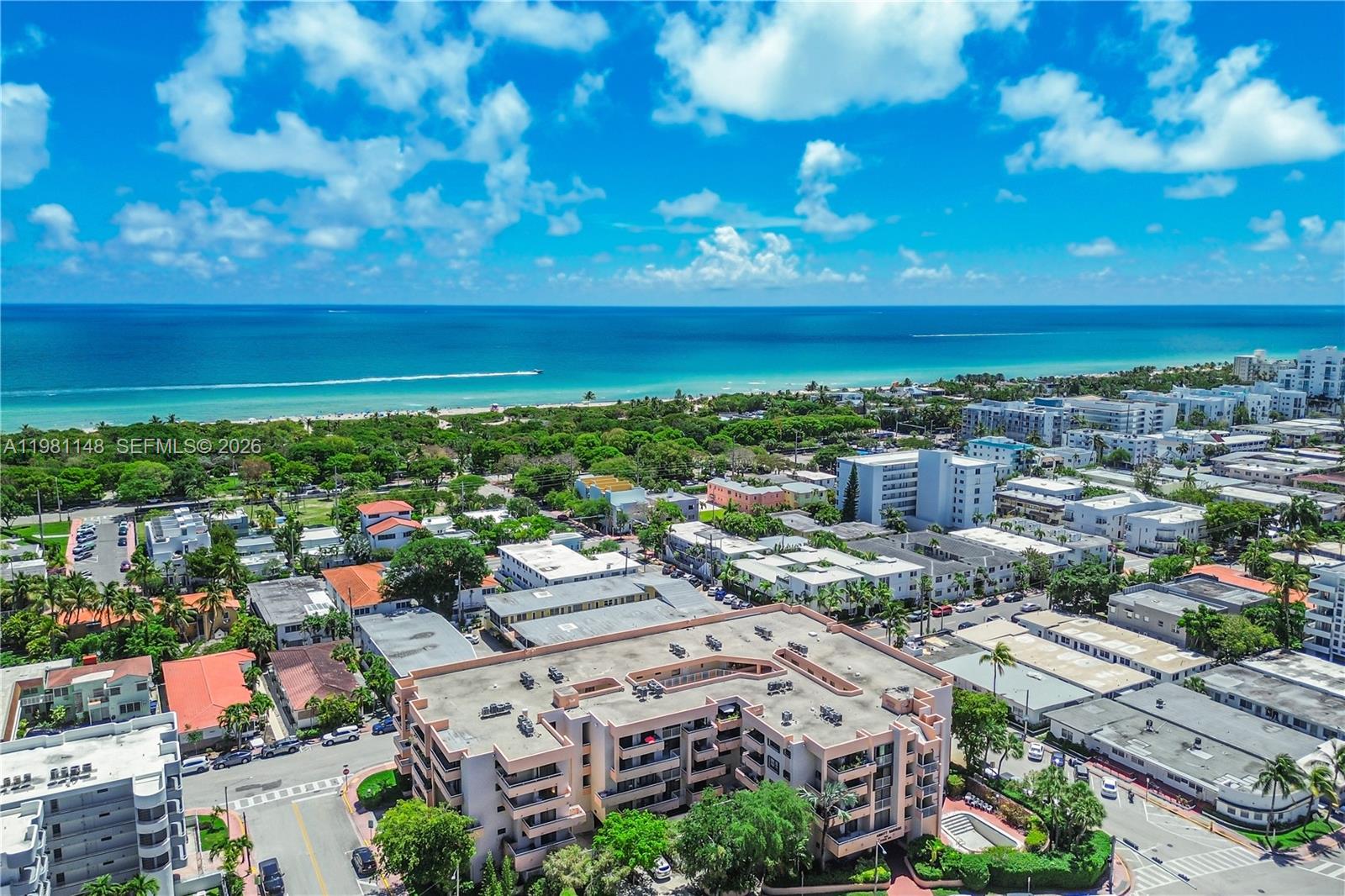 An aerial view shows a multi-story peach-colored apartment building near a beach and ocean — 8101 Byron Ave # 509, Miami Beach FL 33141, MIAMI BEACH, FL