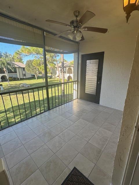 A screened-in balcony features tiled flooring, a ceiling fan, and a view of grassy grounds — 3625 La Aires Court # B2, FL 33463, FL