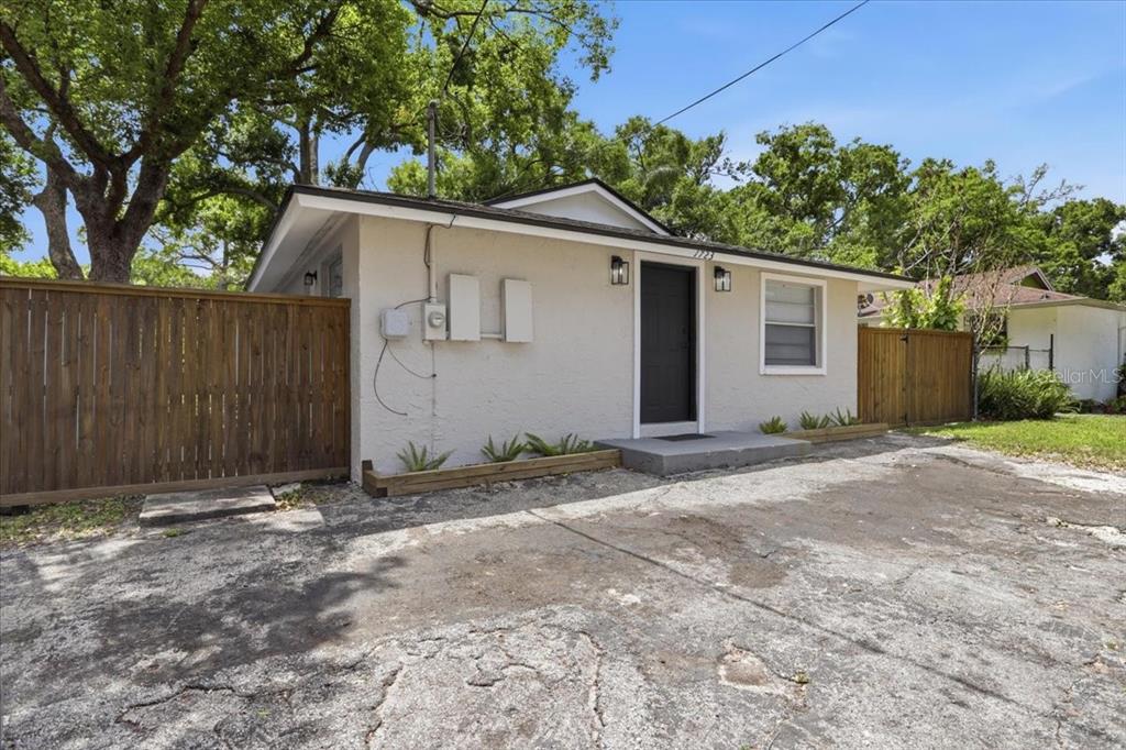 A single-story house with a beige stucco exterior, a dark front door, and a concrete driveway — 1723 E IDELL STREET, TAMPA, FL
