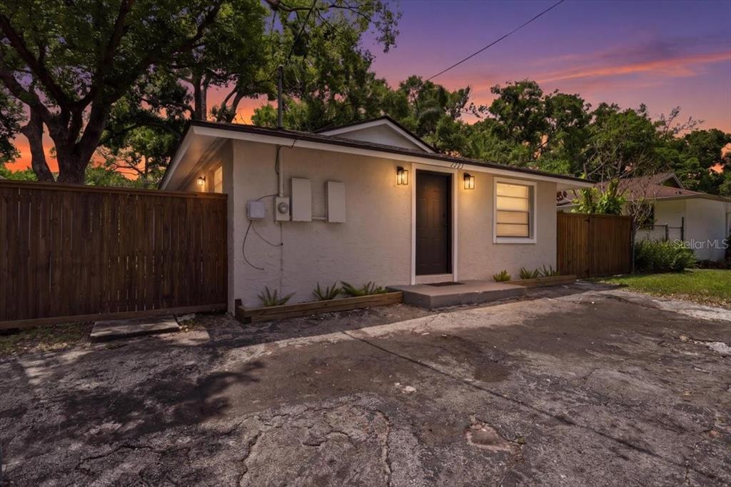 A single-story house with a concrete driveway, dark front door, and wooden privacy fence — 1723 E IDELL STREET, TAMPA, FL