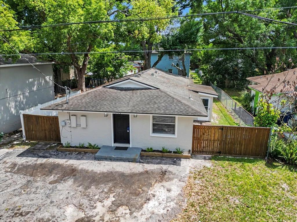 An exterior view of a single-story house with a gray roof and a wooden fence — 1723 E IDELL STREET, TAMPA, FL