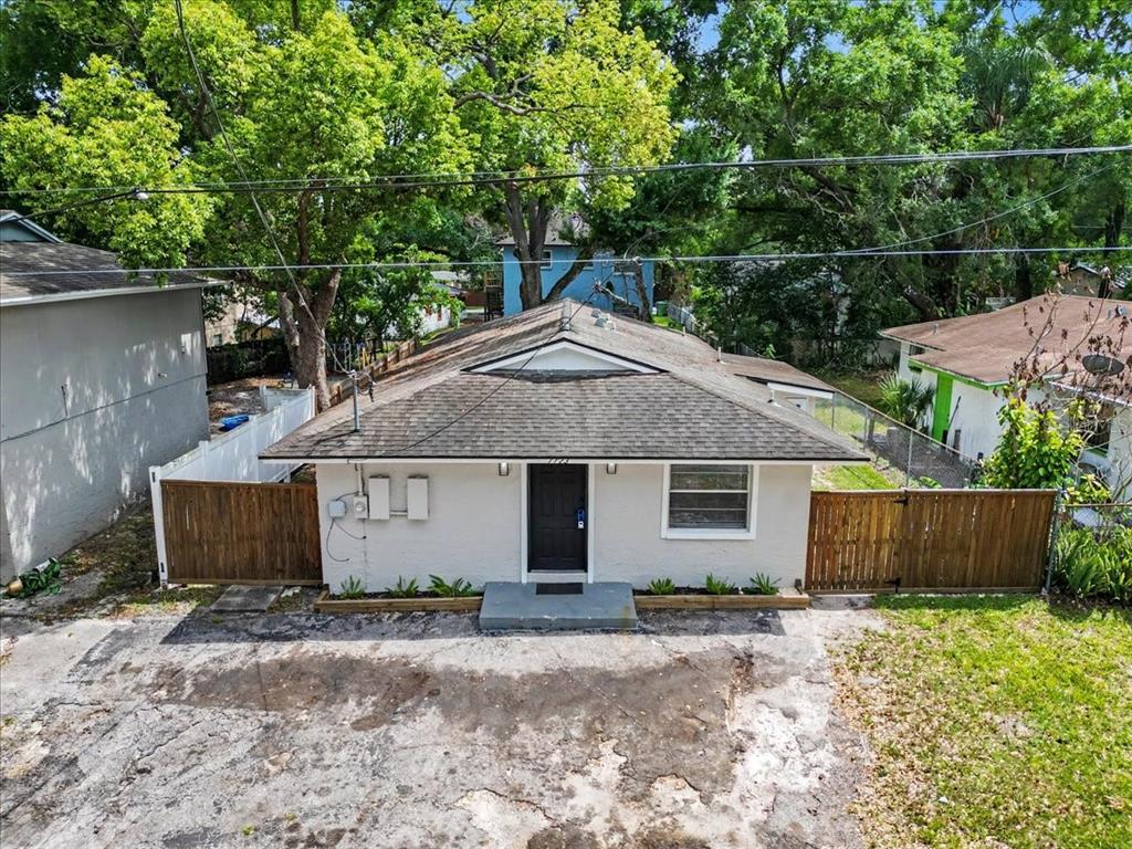 A single-story house with a gray roof, white exterior, and wooden privacy fences — 1723 E IDELL STREET, TAMPA, FL