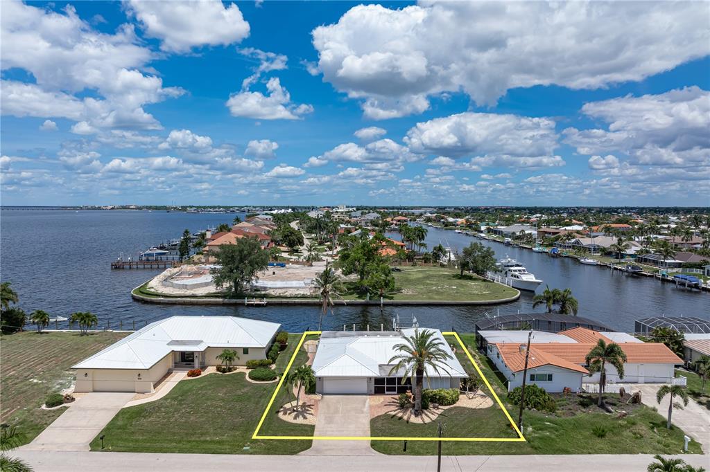 An aerial view shows a single-story house with a white roof and a palm tree — 2211 PALM TREE DRIVE, PUNTA GORDA, FL