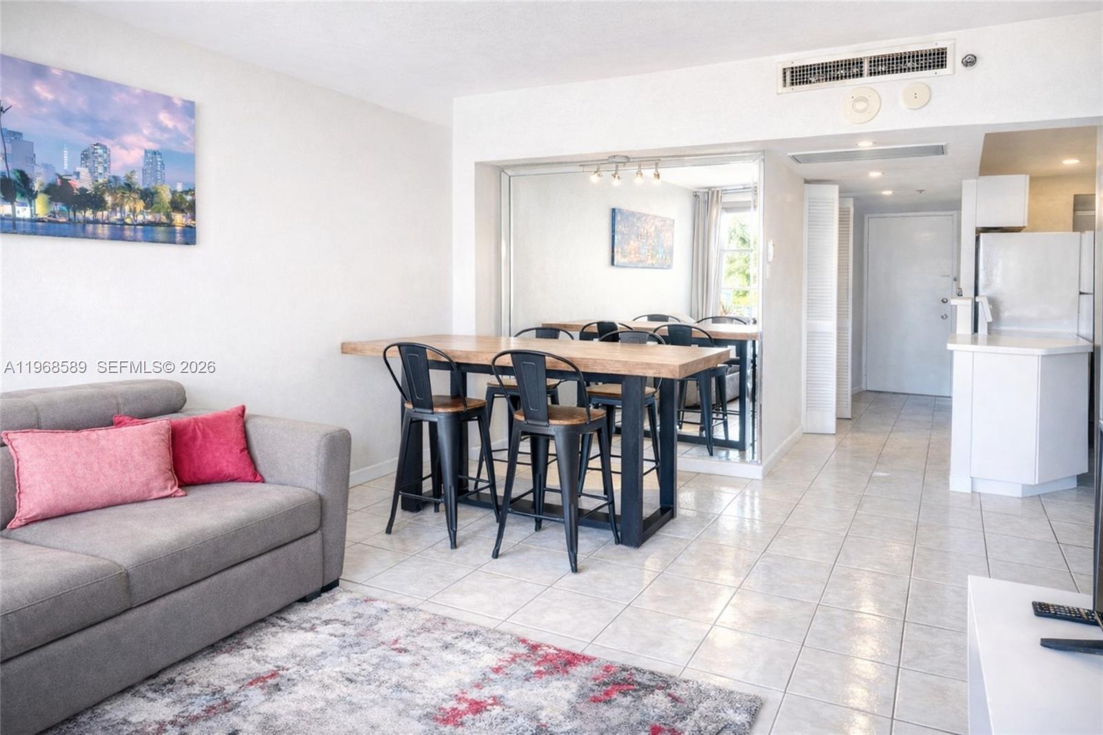 A living and dining area features a grey sofa, a wooden table, and tiled flooring — 100 Lincoln Rd # 415, Miami Beach FL 33139, MIAMI BEACH, FL