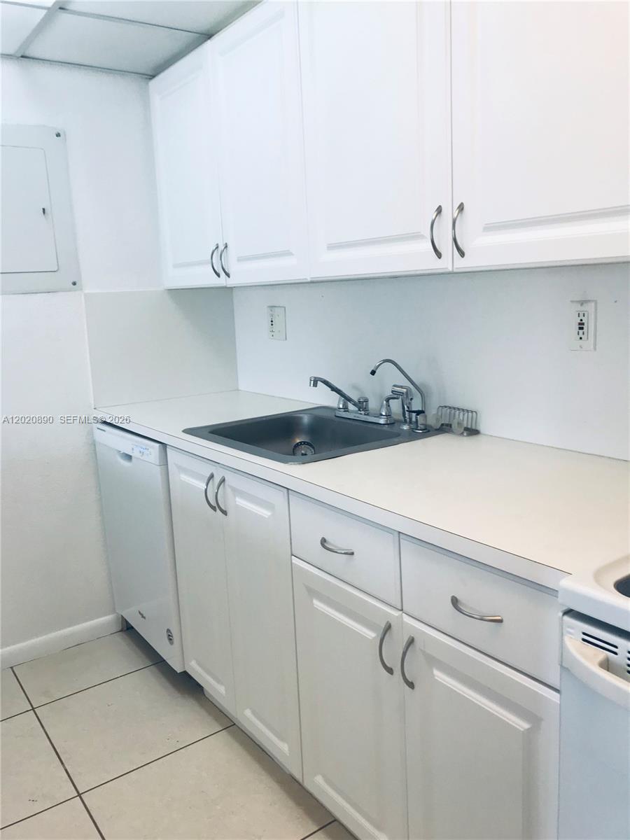 A kitchen features white cabinets, a stainless steel sink, and white appliances — 17600 NW 68th Ave # B3006, Hialeah FL 33015, HIALEAH, FL