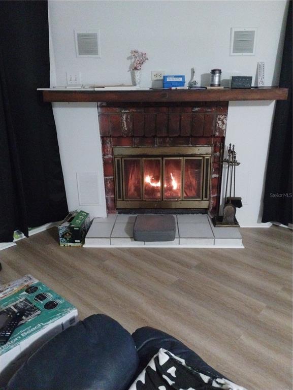 A living room features a brick fireplace with a wooden mantel and a tiled hearth — 5731 90TH AVENUE N, PINELLAS PARK, FL
