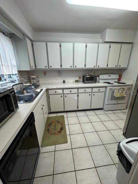 A kitchen features white cabinets, white countertops, a white stove, and light-colored tile flooring — 5731 90TH AVENUE N, PINELLAS PARK, FL