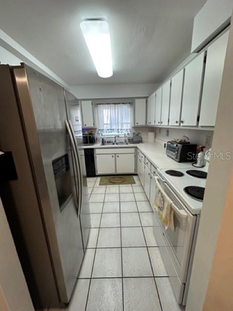 A galley-style kitchen features white cabinets, stainless steel appliances, and light-colored tiled flooring — 5731 90TH AVENUE N, PINELLAS PARK, FL