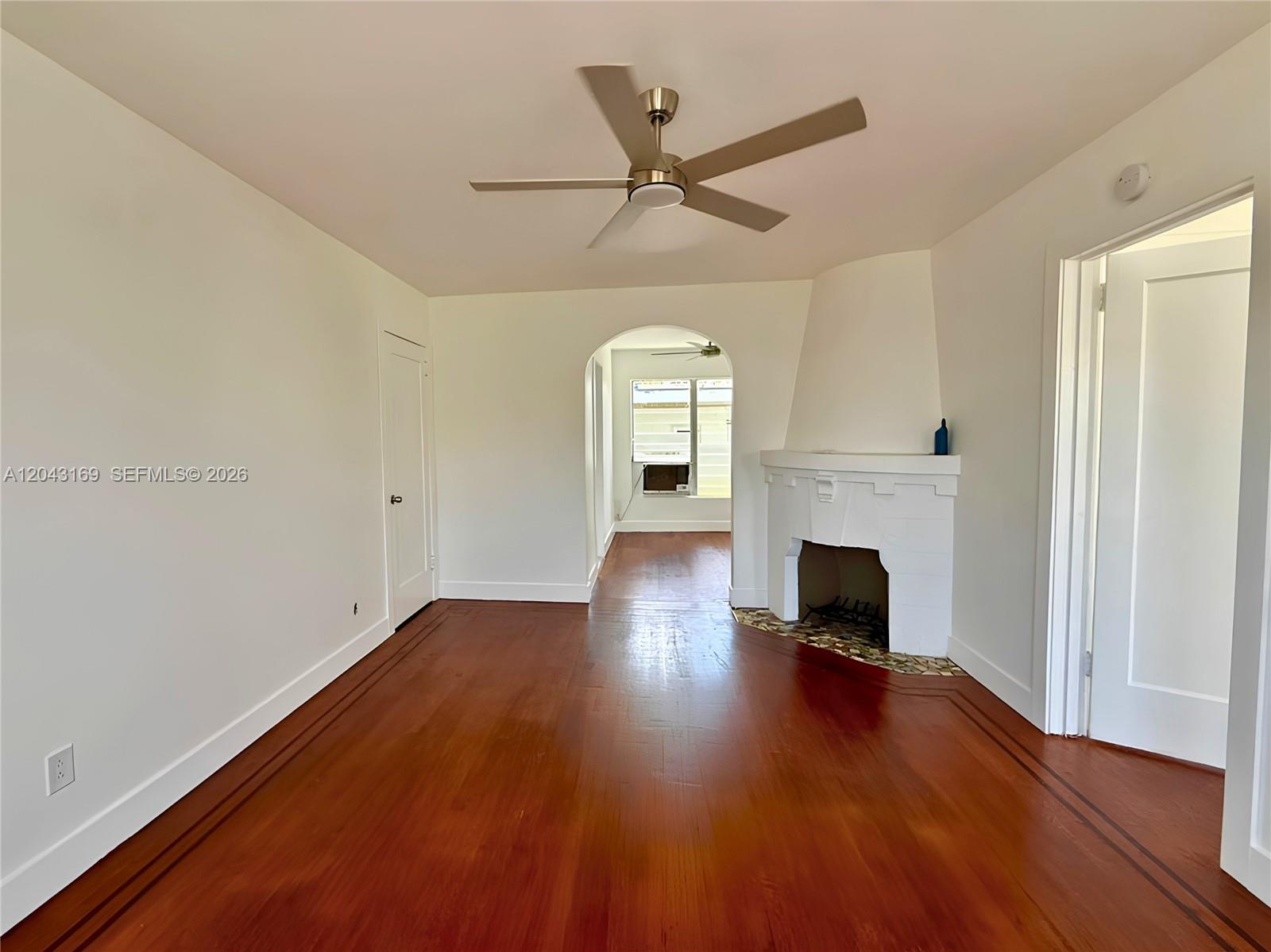 A living room features hardwood floors, a white fireplace, and an arched doorway — 641 10th St # 7, Miami Beach FL 33139, MIAMI BEACH, FL