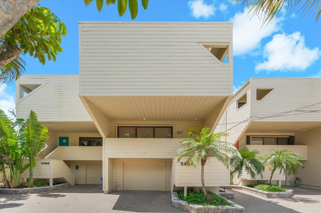 Exterior view of a multi-unit residential building with beige horizontal siding and covered parking — 548A BEACH ROAD, SARASOTA, FL