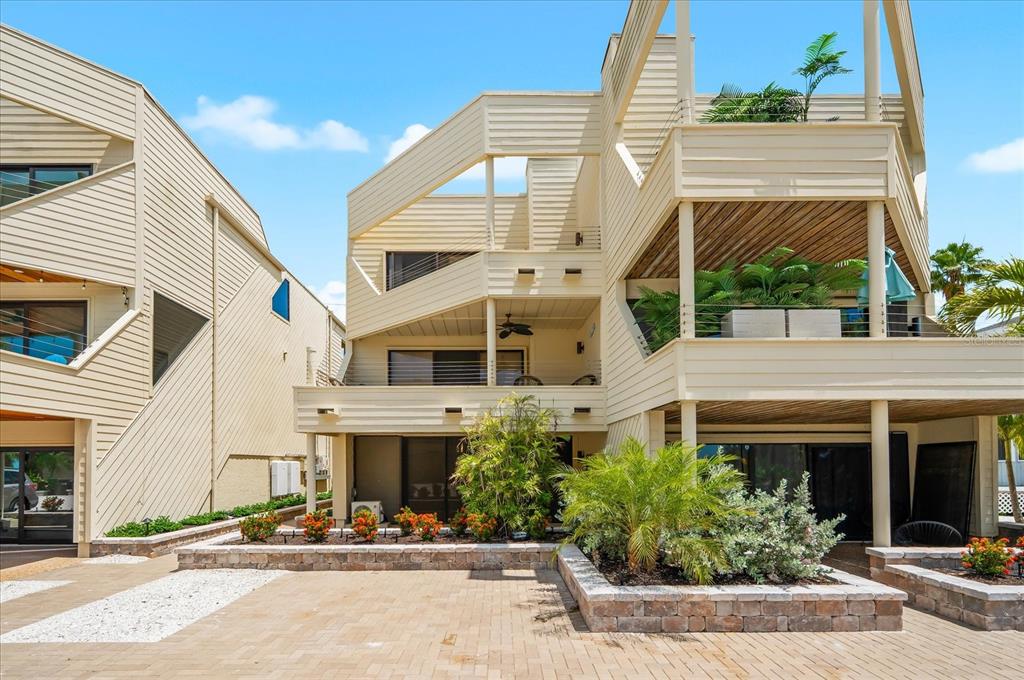A multi-story beige house with balconies, a paved patio, and landscaping in the front yard — 548A BEACH ROAD, SARASOTA, FL