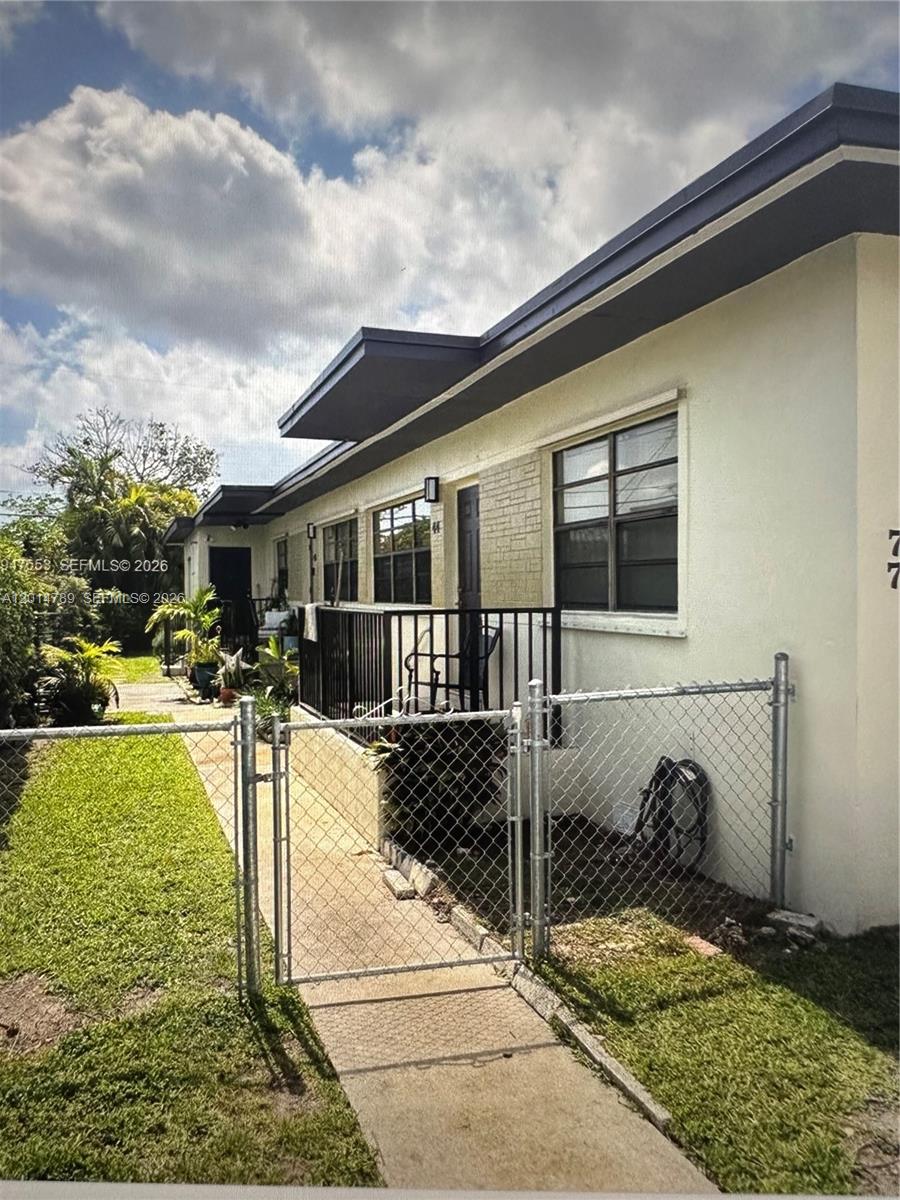 A single-story building exterior features a chain-link fence, a concrete walkway, and black railings — 7546 NW 2nd Ter, Miami FL 33126, MIAMI, FL