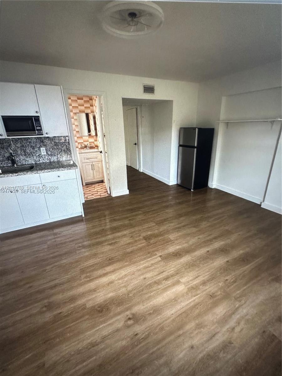 A kitchen area features white cabinets, a stainless steel refrigerator, and wood-look flooring — 7546 NW 2nd Ter, Miami FL 33126, MIAMI, FL