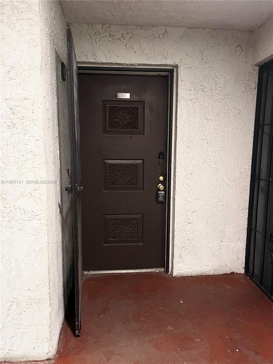 A brown front door with three decorative panels is set into a textured white wall — 4575 S Texas Ave # 307, Orlando FL 32839, ORLANDO, FL