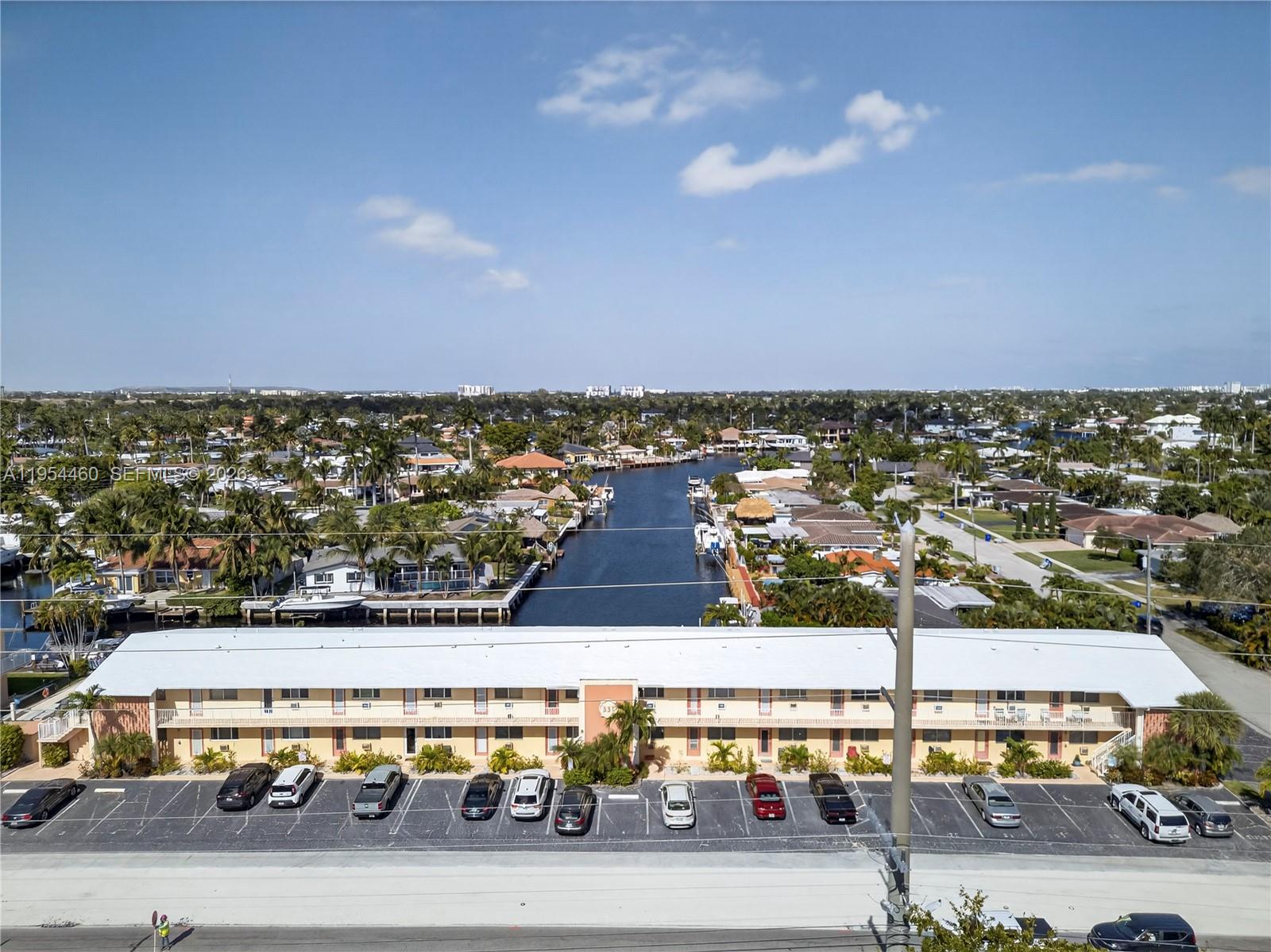 An aerial view shows a long, two-story apartment building with a parking lot and canal — 331 E Mcnab Rd # 226, Pompano Beach FL 33060, POMPANO BEACH, FL