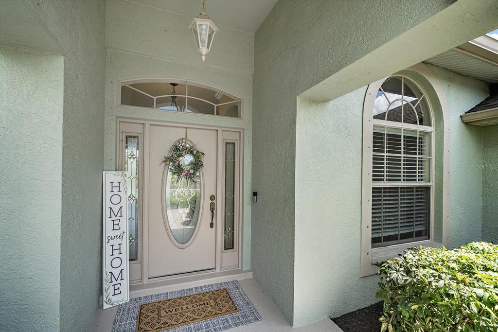 A front entryway features a light green exterior, a white door with glass, and a welcome mat — 12111 SUMMER MEADOW DRIVE, LAKEWOOD RANCH, FL