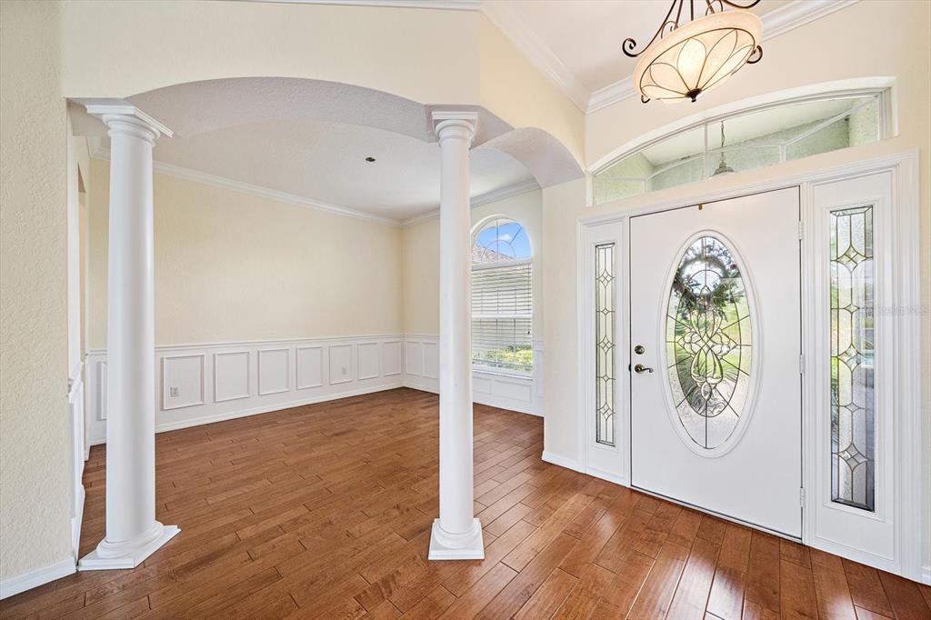 An entryway with hardwood floors, white columns, wainscoting, and a glass-paneled front door — 12111 SUMMER MEADOW DRIVE, LAKEWOOD RANCH, FL