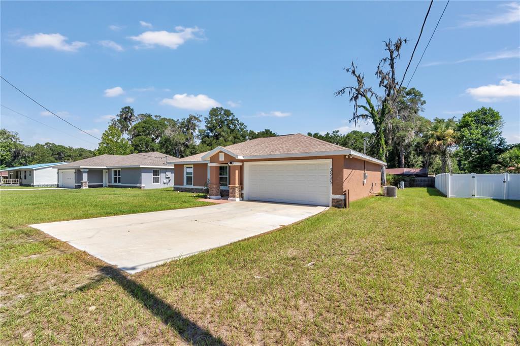 A tan single-story house with a white garage door and a concrete driveway — 3535 SE 131ST PLACE, BELLEVIEW, FL