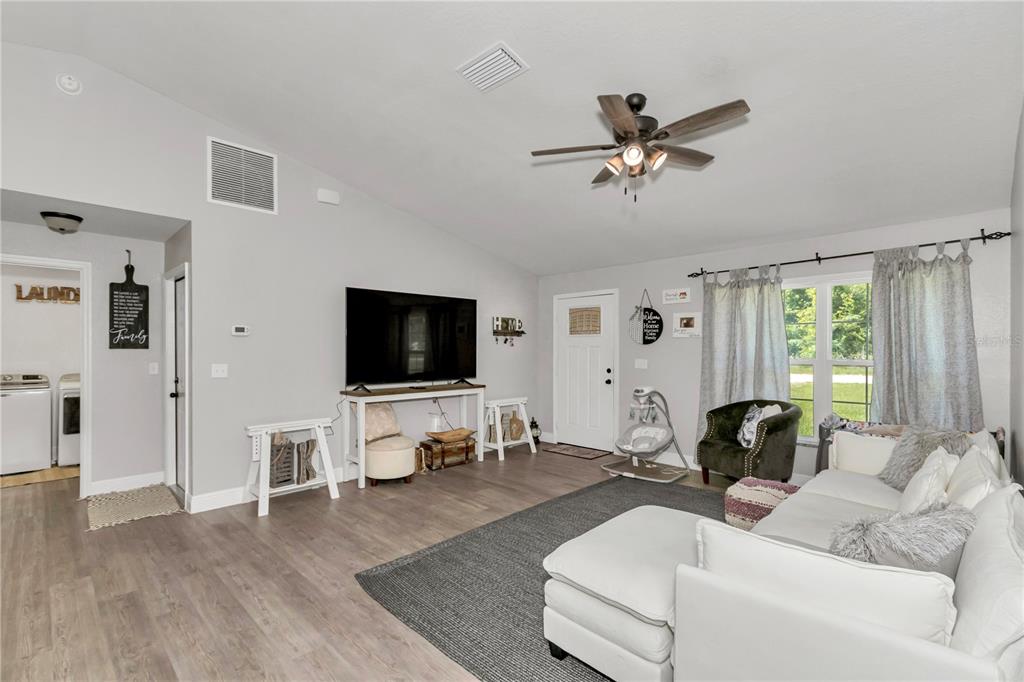 A living room features light gray walls, wood-look flooring, a ceiling fan, and a white sofa — 3535 SE 131ST PLACE, BELLEVIEW, FL