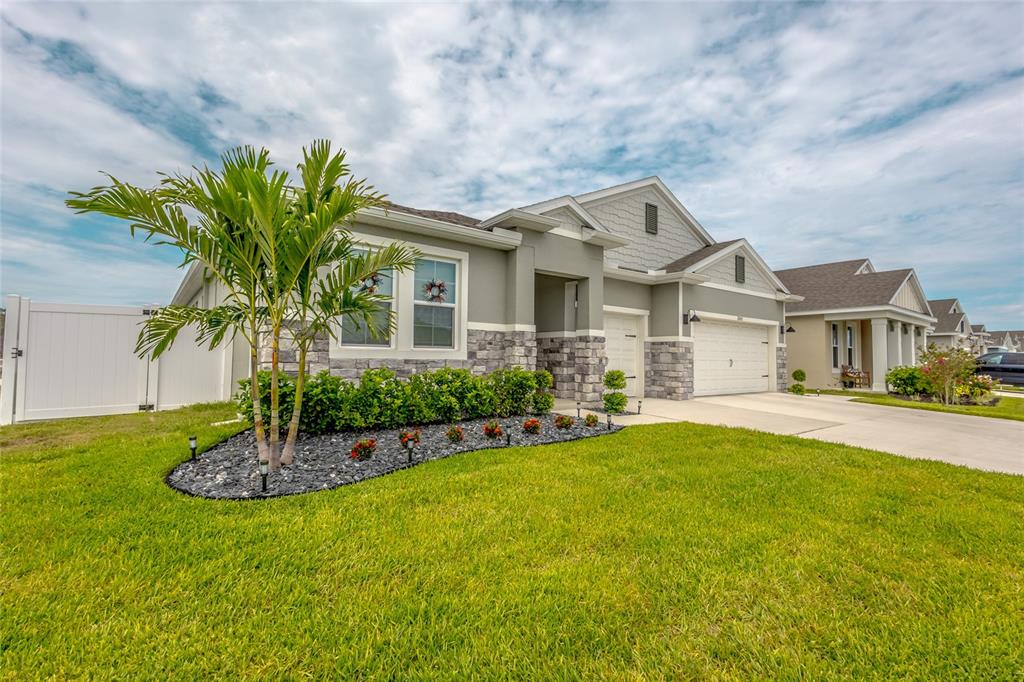 A single-story suburban house with a stone facade, palm tree, and attached garage — 2843 ELIO HAMMOCK DRIVE, ST CLOUD, FL