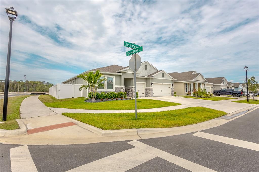 A corner lot features a single-story house with a stone facade and a white fence — 2843 ELIO HAMMOCK DRIVE, ST CLOUD, FL