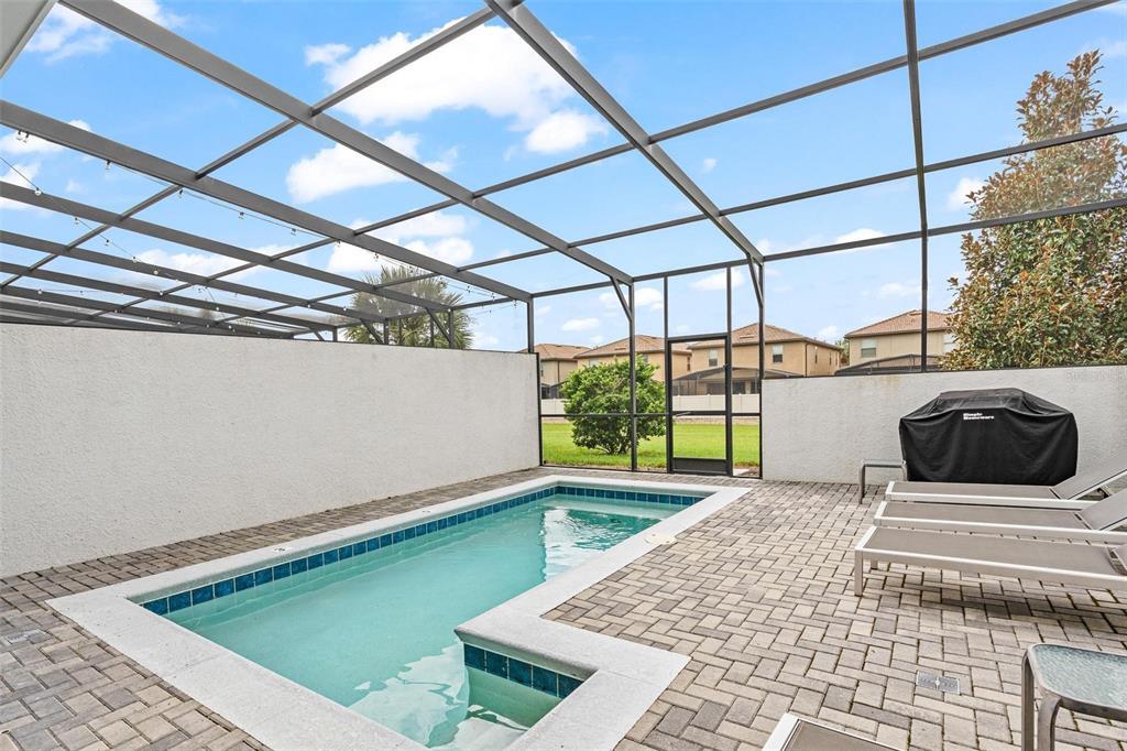 A rectangular swimming pool sits on a paved patio enclosed by a screened-in lanai — 8936 SYDNEY AVENUE, KISSIMMEE, FL