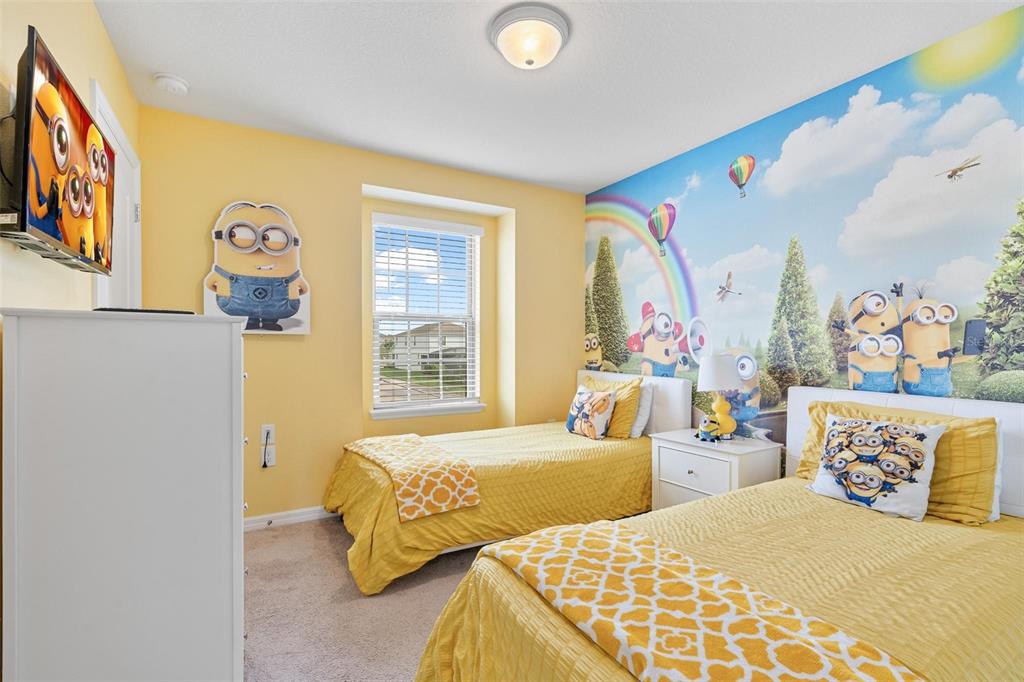 A bedroom features two twin beds, yellow walls, and a large Minions-themed wall mural — 8936 SYDNEY AVENUE, KISSIMMEE, FL