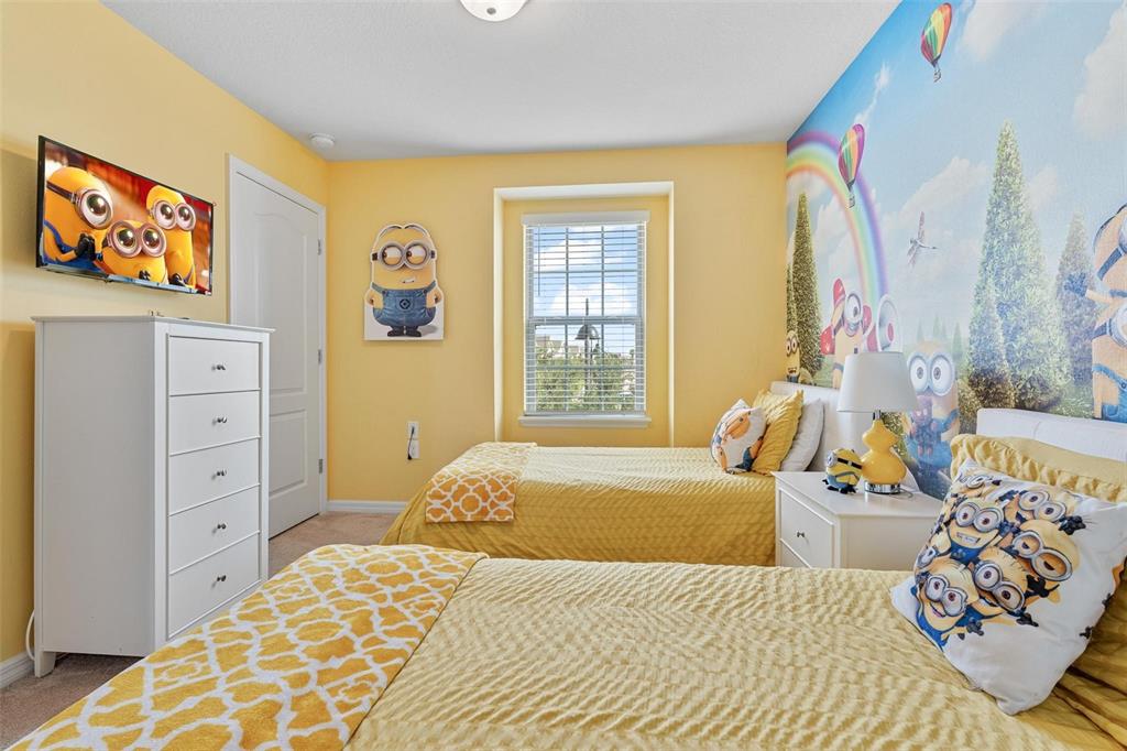 A bedroom features two twin beds, yellow walls, and a Minion-themed wall mural — 8936 SYDNEY AVENUE, KISSIMMEE, FL