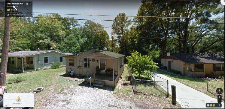 Three small, single-story houses sit side-by-side on a grassy lot with gravel driveways — NW 157TH AVE, ALACHUA, FL