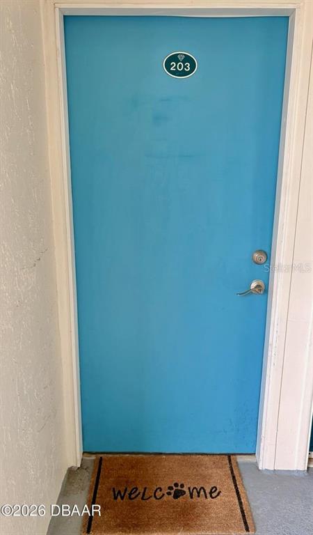 A bright blue door with a room number sign and a paw-print welcome mat — 935 S ATLANTIC AVENUE UNIT 203, DAYTONA BEACH, FL