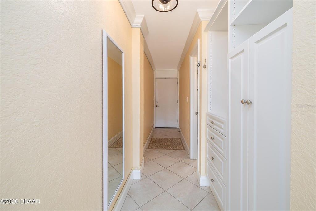 A hallway features light-colored walls, tile flooring, a full-length mirror, and white built-in cabinetry — 935 S ATLANTIC AVENUE UNIT 203, DAYTONA BEACH, FL