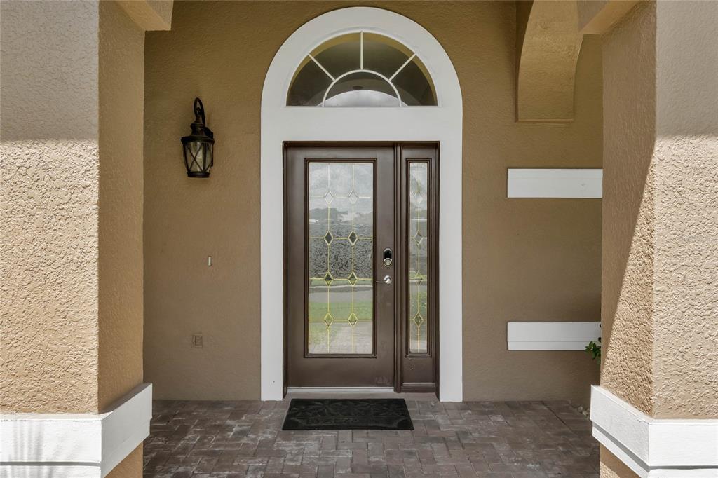 A brown front door with a glass insert and arched transom window under a porch — 7973 SEA PEARL CIRCLE, KISSIMMEE, FL