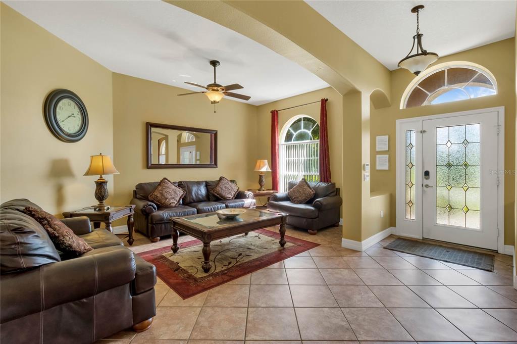 A living room with tile floors, leather furniture, and a front door with glass panels — 7973 SEA PEARL CIRCLE, KISSIMMEE, FL