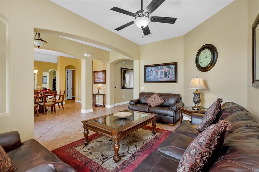 A living room features leather sofas, a glass-topped coffee table, and a ceiling fan — 7973 SEA PEARL CIRCLE, KISSIMMEE, FL