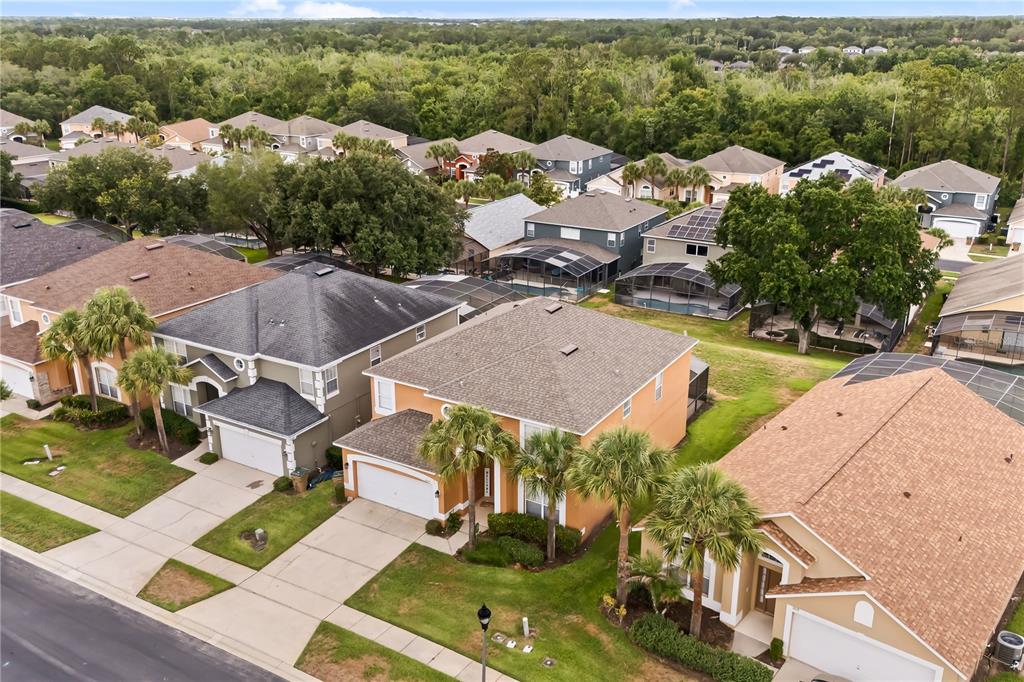 An aerial view shows several suburban houses with driveways, lawns, and screened-in pool enclosures — 8675 LA ISLA DRIVE, KISSIMMEE, FL