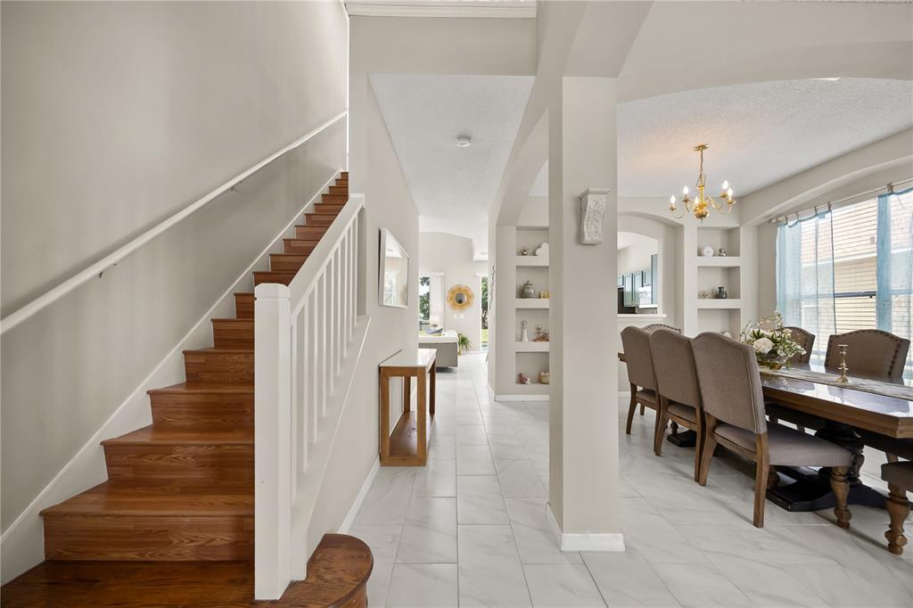 A staircase with wood treads leads to an upper level beside a dining room area — 8675 LA ISLA DRIVE, KISSIMMEE, FL