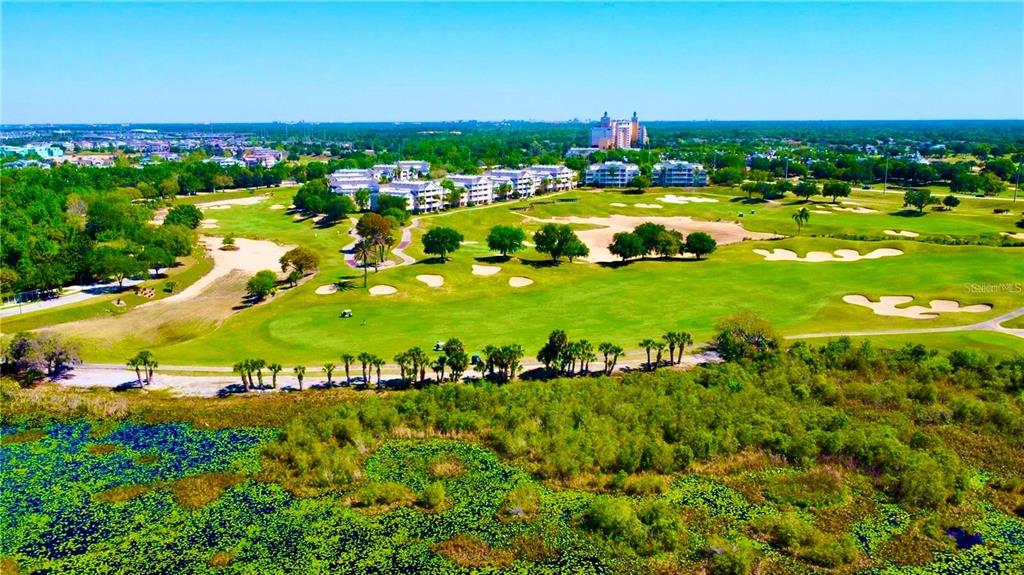 An aerial view shows a golf course with sand traps, trees, and nearby residential buildings — 1440 REUNION BOULEVARD, REUNION, FL