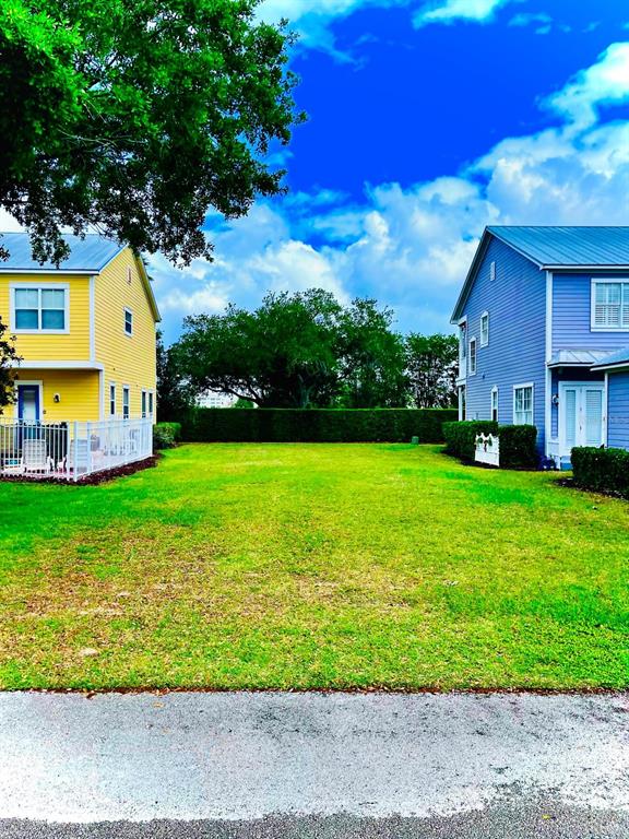 A vacant grassy lot sits between a yellow house and a blue house — 1440 REUNION BOULEVARD, REUNION, FL