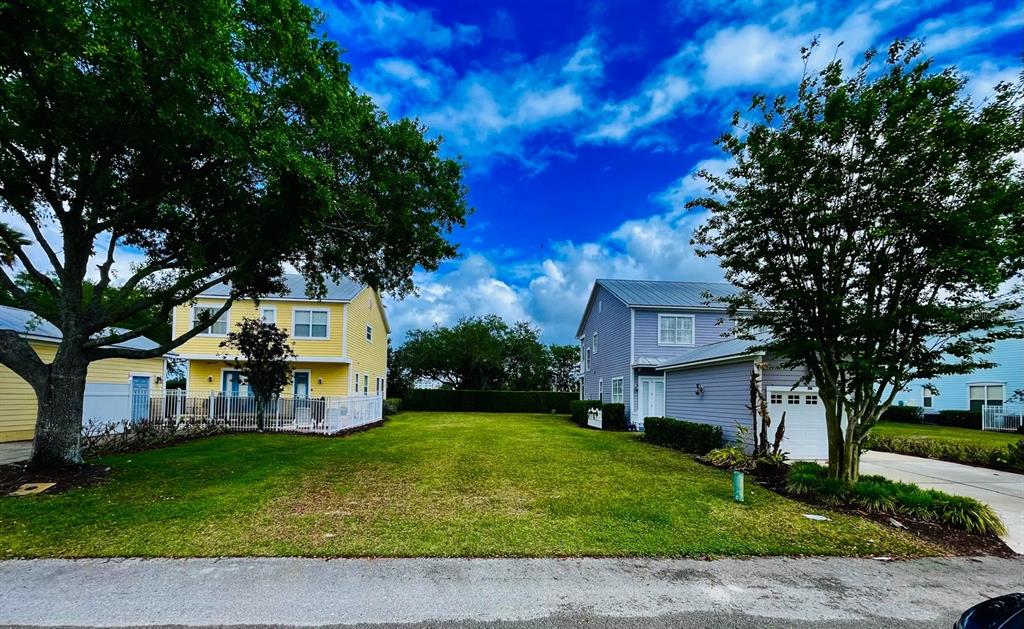 A grassy vacant lot sits between two two-story houses under a blue sky — 1440 REUNION BOULEVARD, REUNION, FL