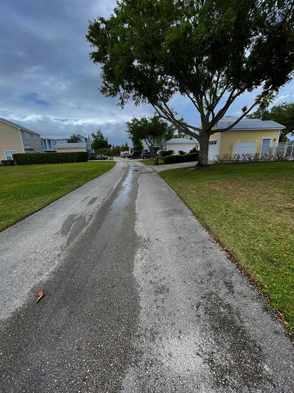 A paved driveway leads toward houses under a large tree on a cloudy day — 1440 REUNION BOULEVARD, REUNION, FL