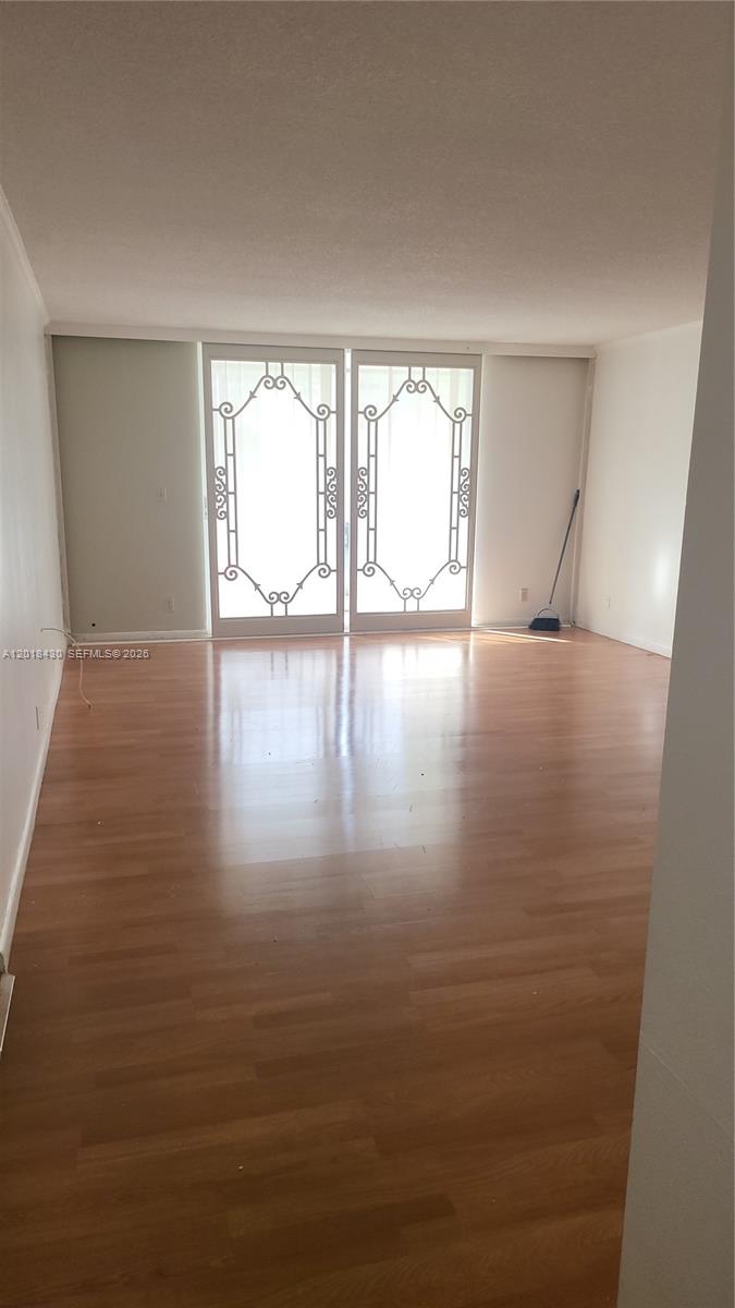 An empty room features light wood-look flooring and a large set of decorative glass doors — 1001 NE 14th Ave # 201, Hallandale Beach FL 33009, HALLANDALE BEACH, FL
