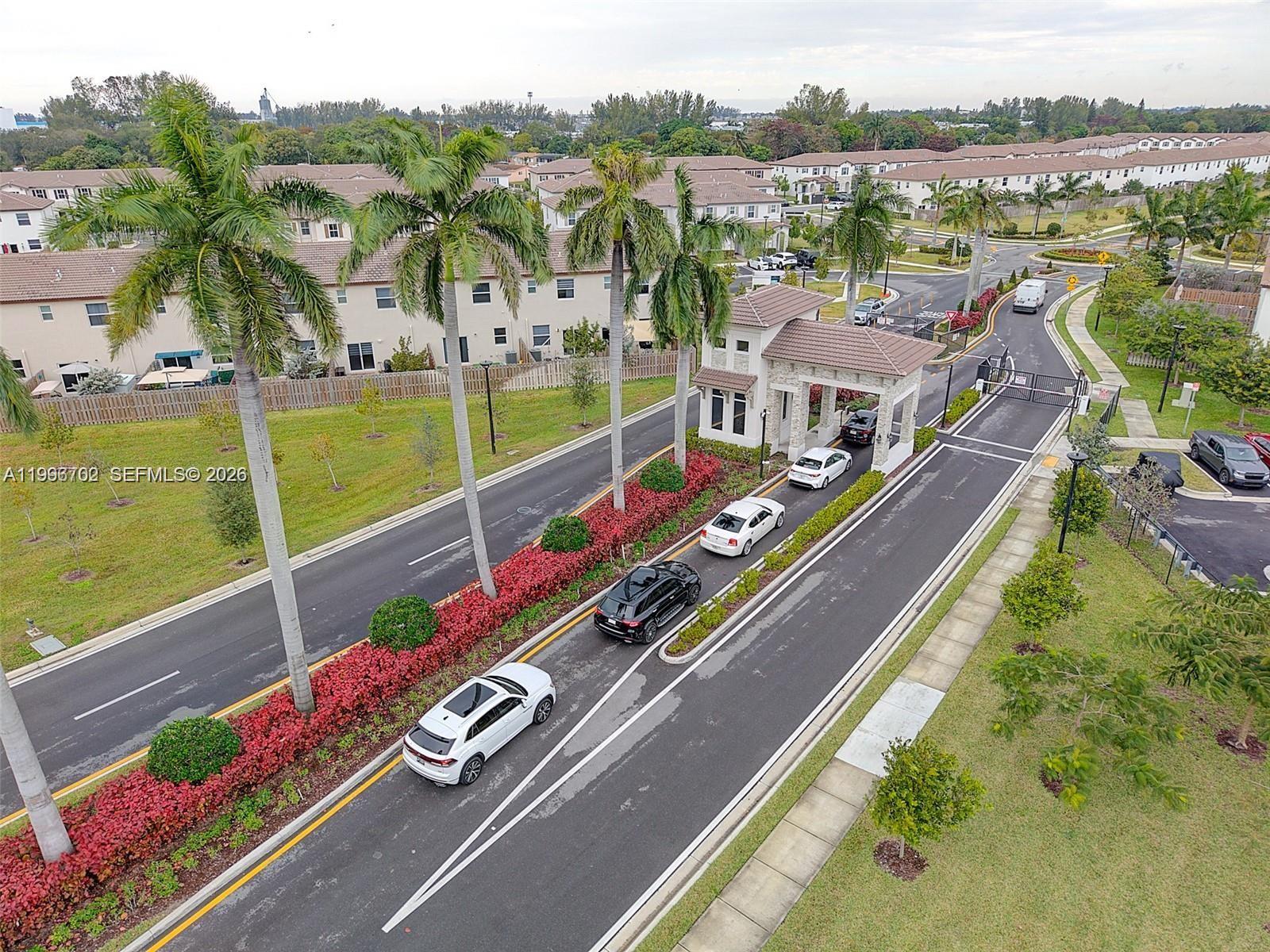 An aerial view shows a gated community entrance with cars lined up on the road — 12774 NW 23rd Pl, Miami FL 33167, MIAMI, FL
