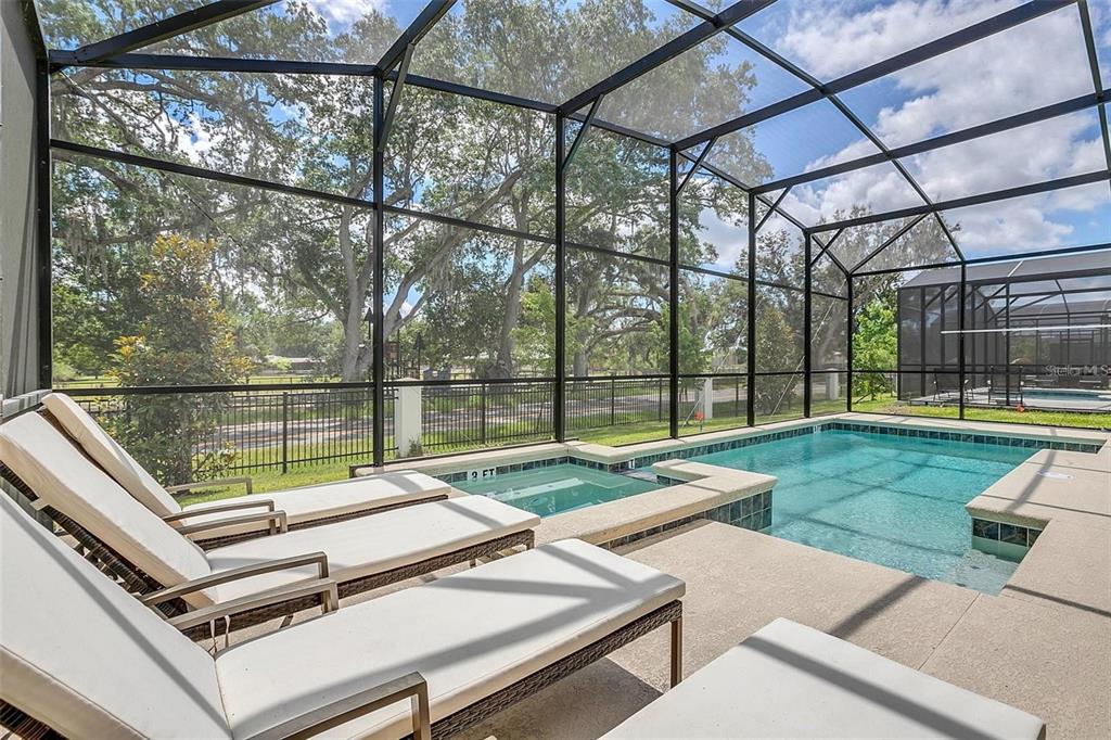 A screened-in pool and hot tub area with lounge chairs on a concrete patio — 2547 SHANTI DRIVE, KISSIMMEE, FL
