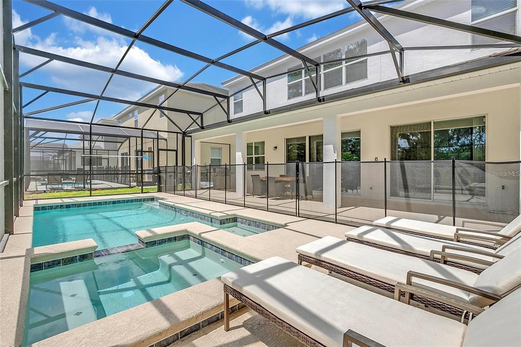 A screened-in patio features a swimming pool, a spa, and lounge chairs on a deck — 2547 SHANTI DRIVE, KISSIMMEE, FL