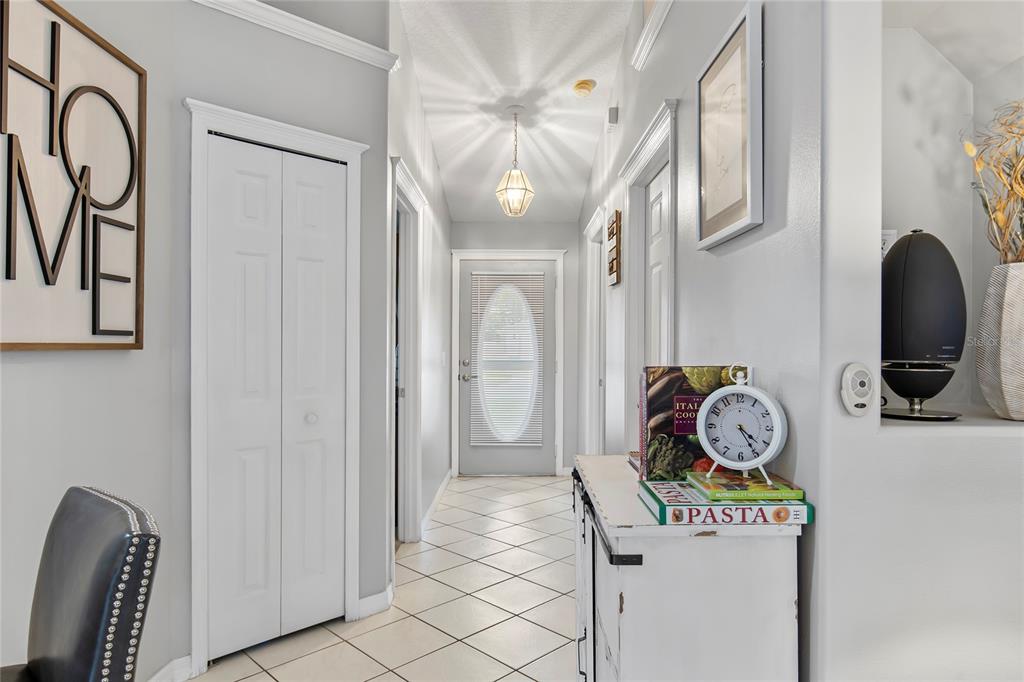 A hallway with light-colored tile floors, a white console table, and a glass-paneled front door — 102 EASTWOOD DRIVE, PALM COAST, FL