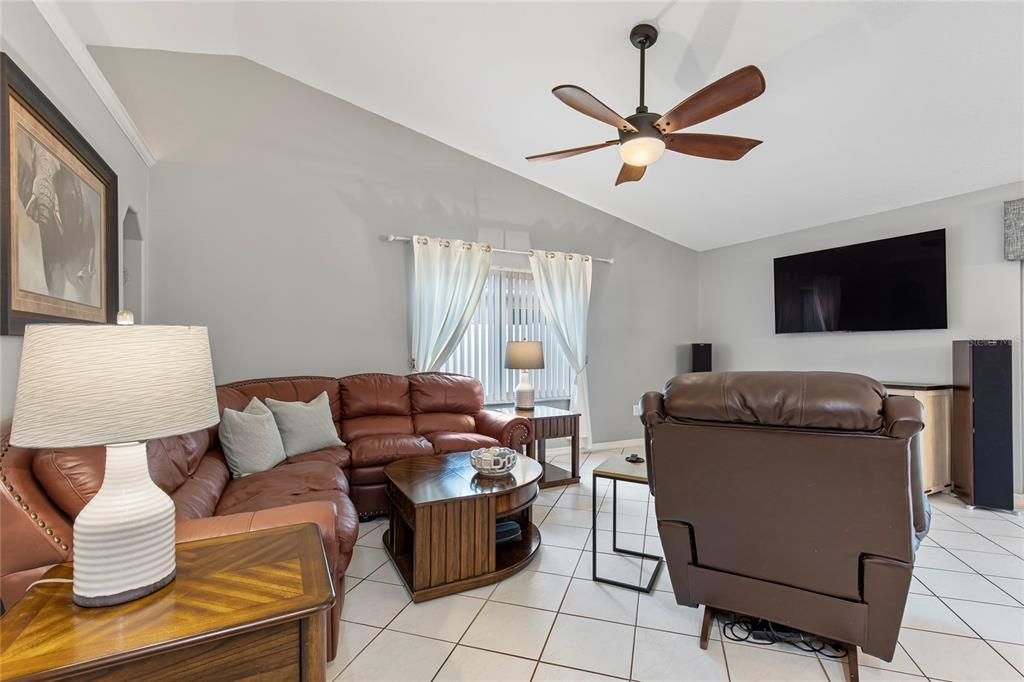 A living room features a leather sectional, a recliner, a ceiling fan, and tile flooring — 102 EASTWOOD DRIVE, PALM COAST, FL