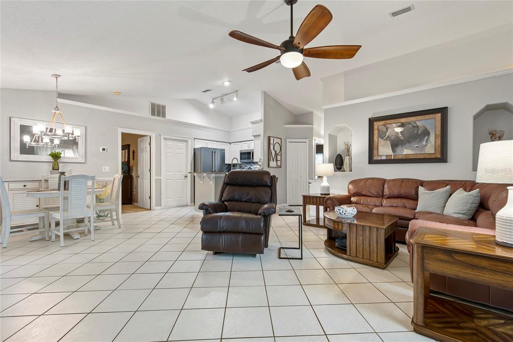 A living room and dining area with tile floors, a ceiling fan, and leather furniture — 102 EASTWOOD DRIVE, PALM COAST, FL