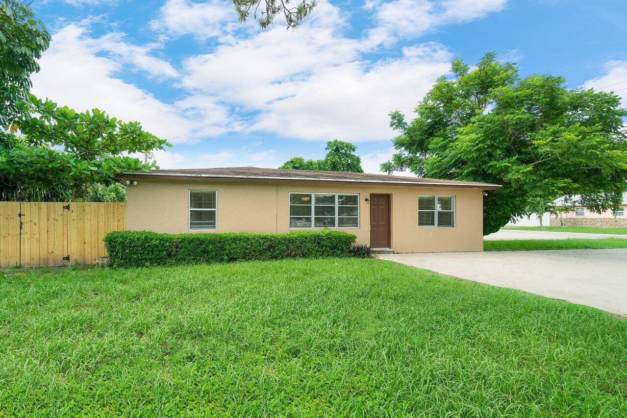 A single-story tan house with a brown door, a concrete driveway, and a wooden fence — 5854 Kumquat Road # A, FL 33413, FL